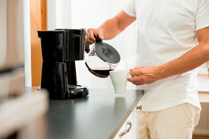 man pouring hot coffee from a coffee pot