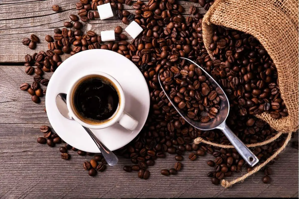 a cup of black coffee next to a bag of roasted beans.