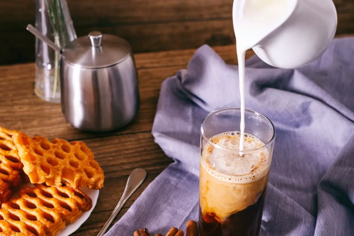 adding coffee creamer to a coffee brew.