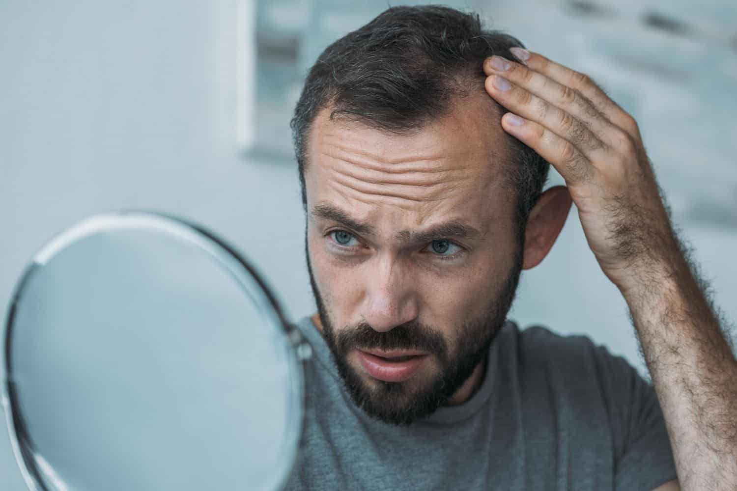 coffee loving man checking the mirror to see if he is losing hair.