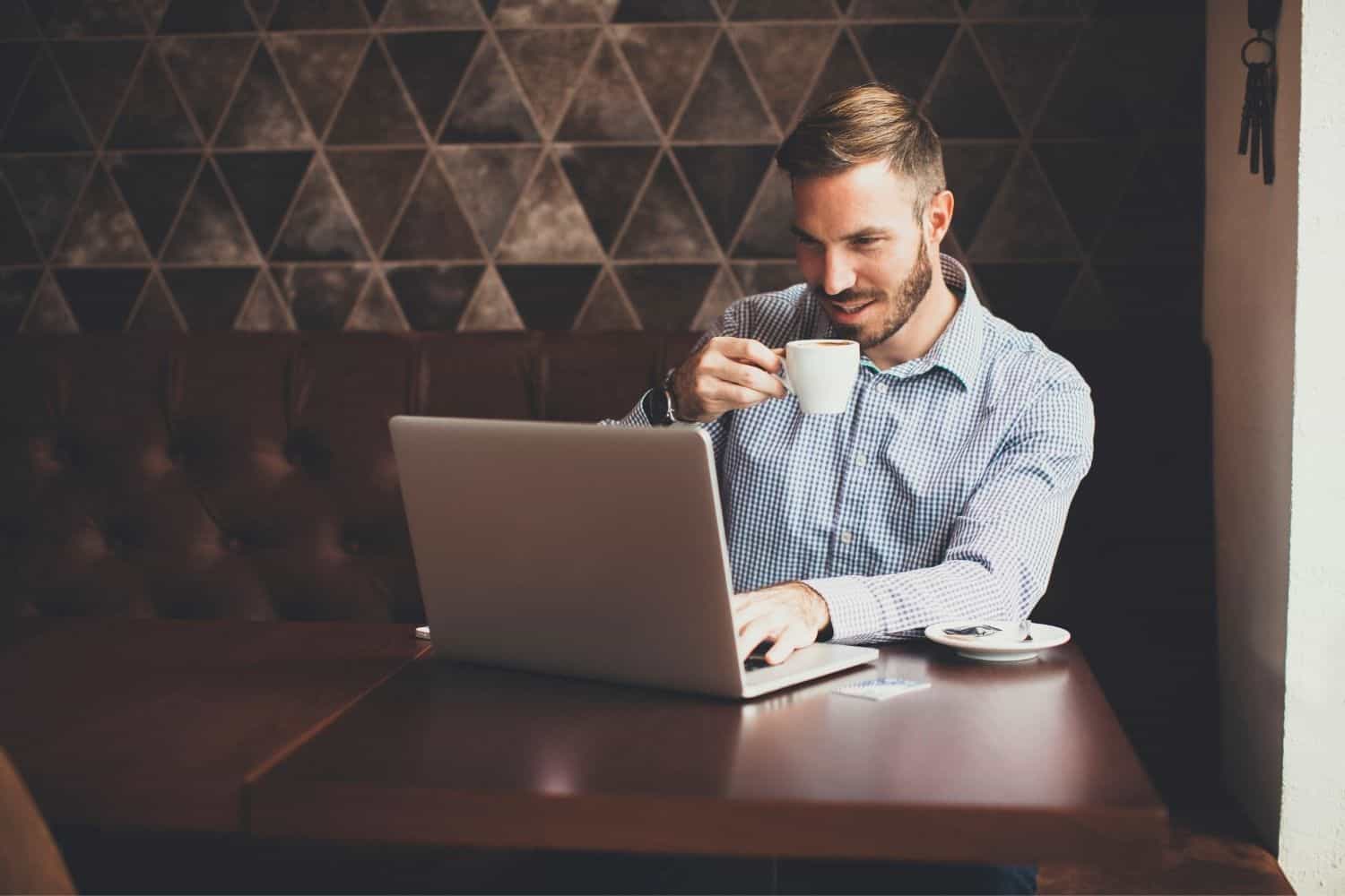 man enjoying decaf coffee while working on his laptop