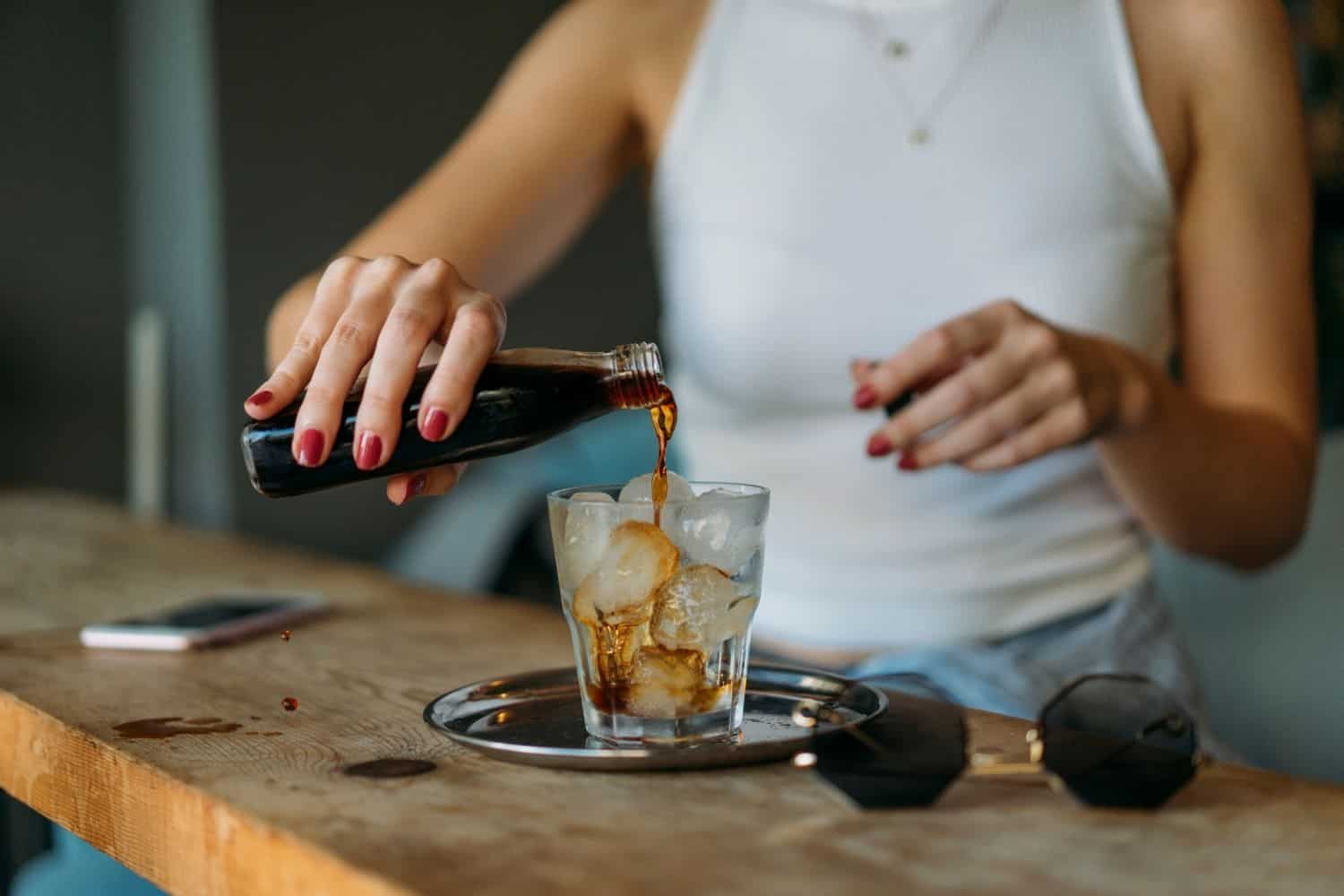 woman pouring cold brew coffee into a glass.