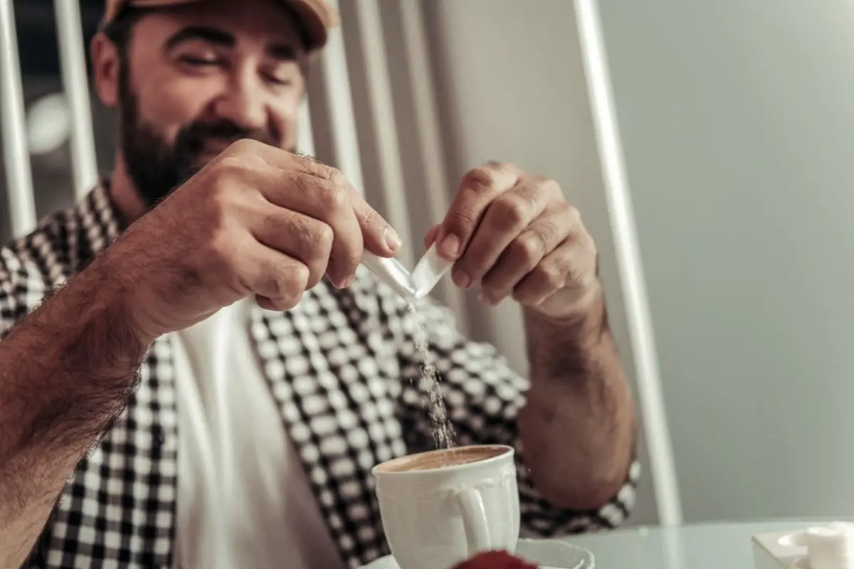 man adding artificial sweetener to make coffee sweet