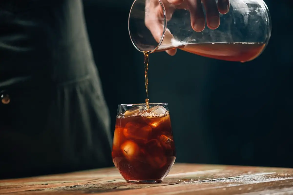 man pouring cold brew coffee into a glass