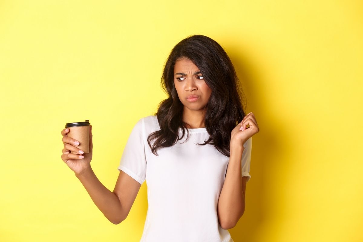woman making an unpleasant face after drinking bitter coffee