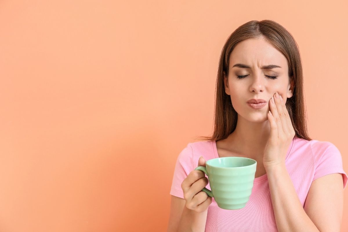 woman with teeth cavity issues holding a cup of coffee