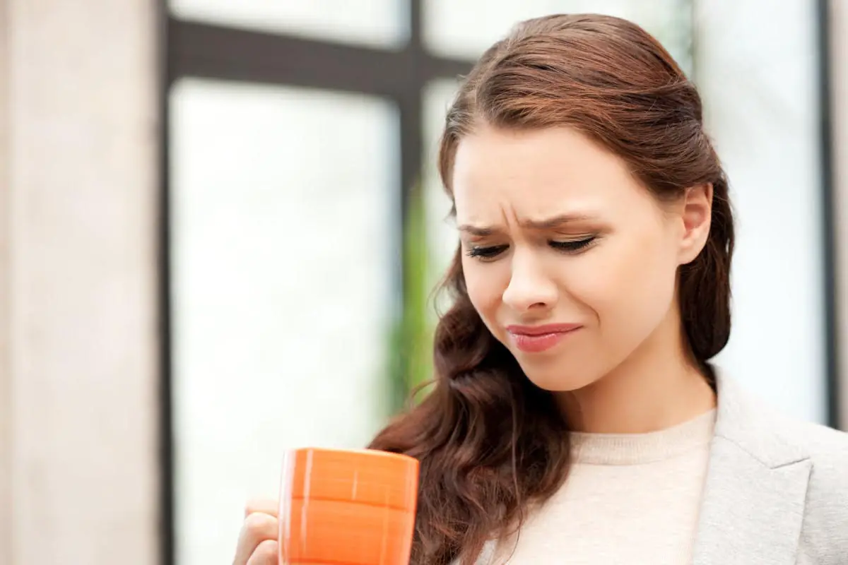 girl holding coffee mug with dull face expression