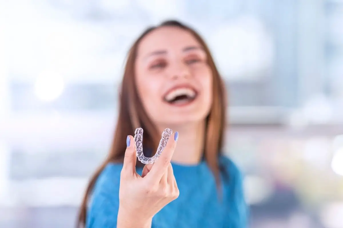 woman holding her invisalign braces after drinking coffee