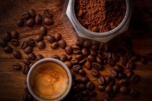 brown coffee beans beside white ceramic mug