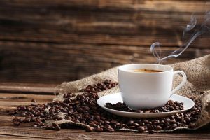 Cup of coffee with coffee beans on a brown wooden background