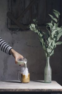 person pouring milk on glass mason jar 1