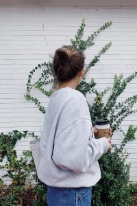 woman in gray sweater holding mug