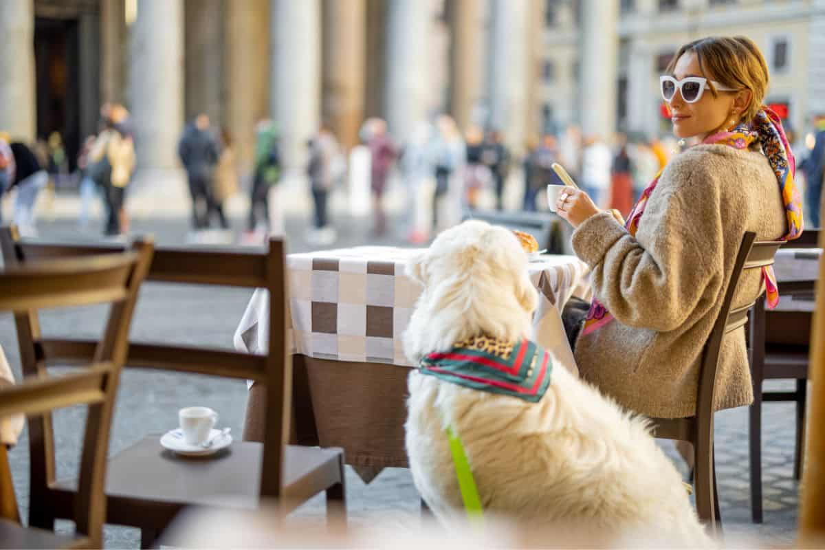 woman with a dog sitting outside a cafe