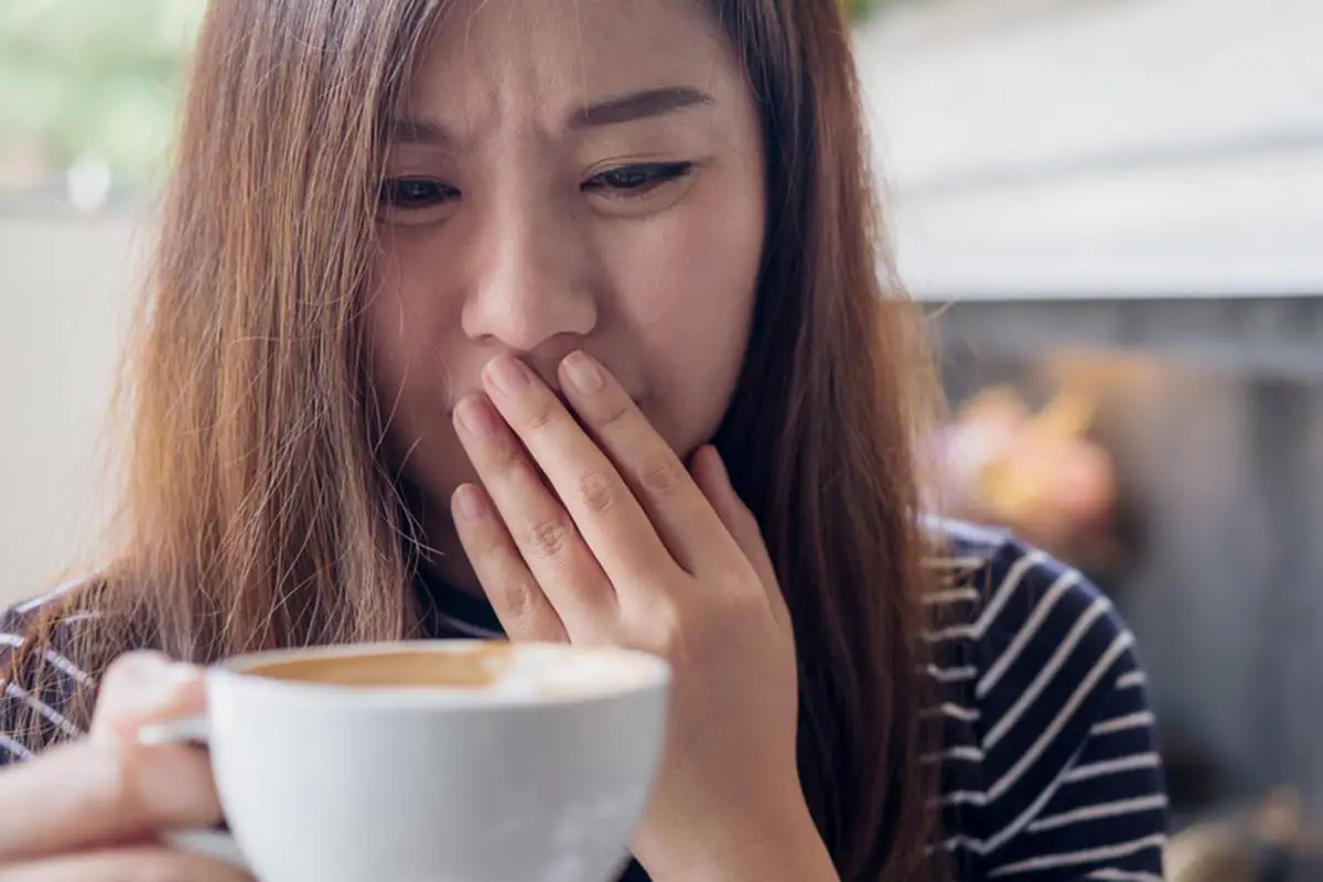 girl holding a bad smelling coffee cup