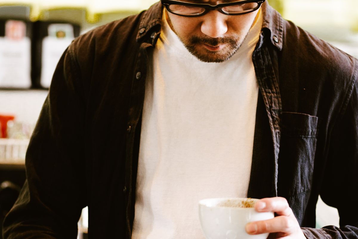 man looking at his cup of coffee and wondering why it's cloudy