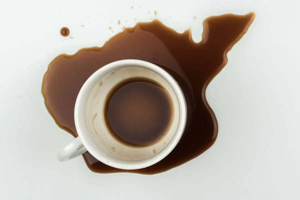 Top View Of A Cup Of Coffee And Spilled Coffee On The White Tabl